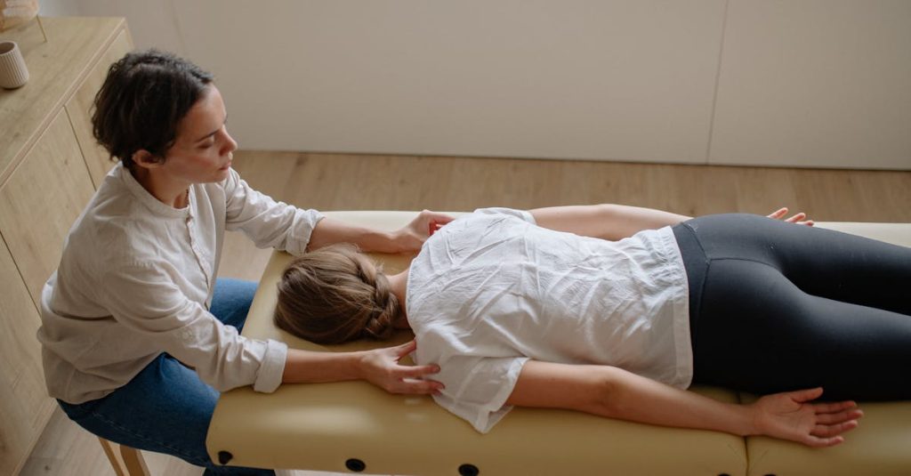 A therapist performs a chiropractic adjustment on a woman lying on a treatment table indoors.